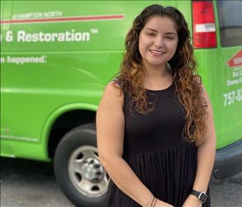 SERVPRO female employee smiling in front of green trucks